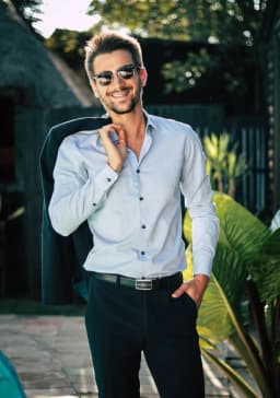 Man wearing sunglasses and a light blue shirt with a jacket over his shoulder — illustrative style reference