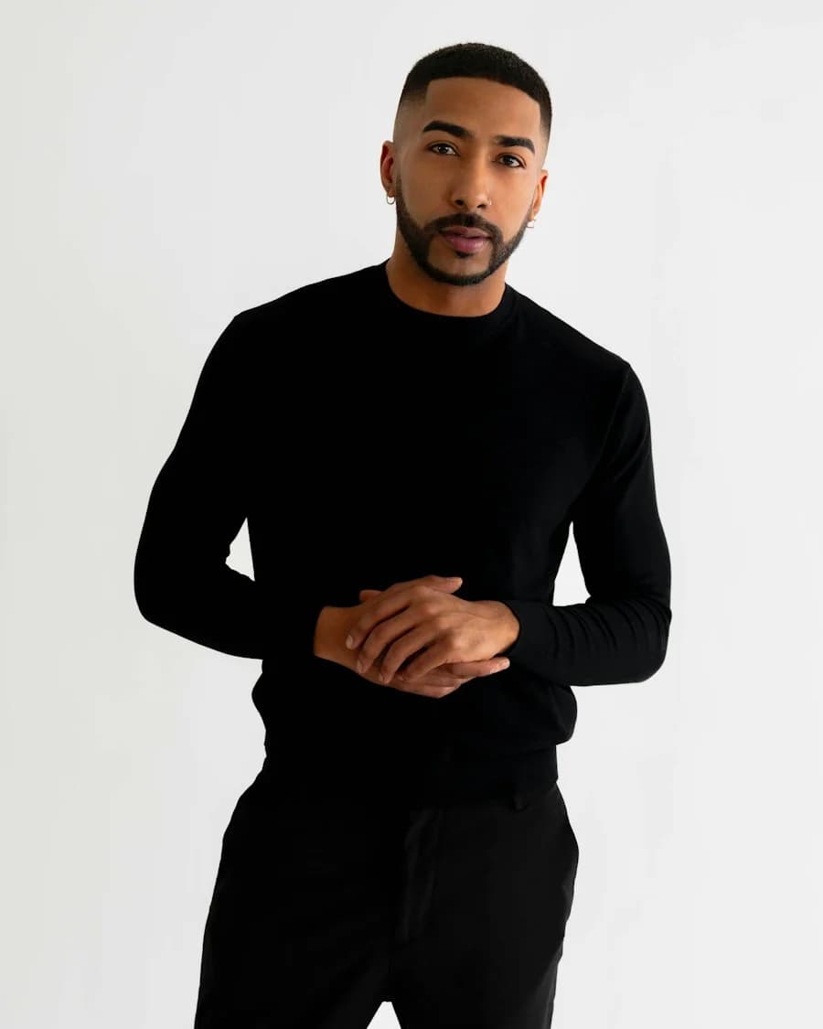 Man wearing a black sweater against a light studio background — illustrative style reference